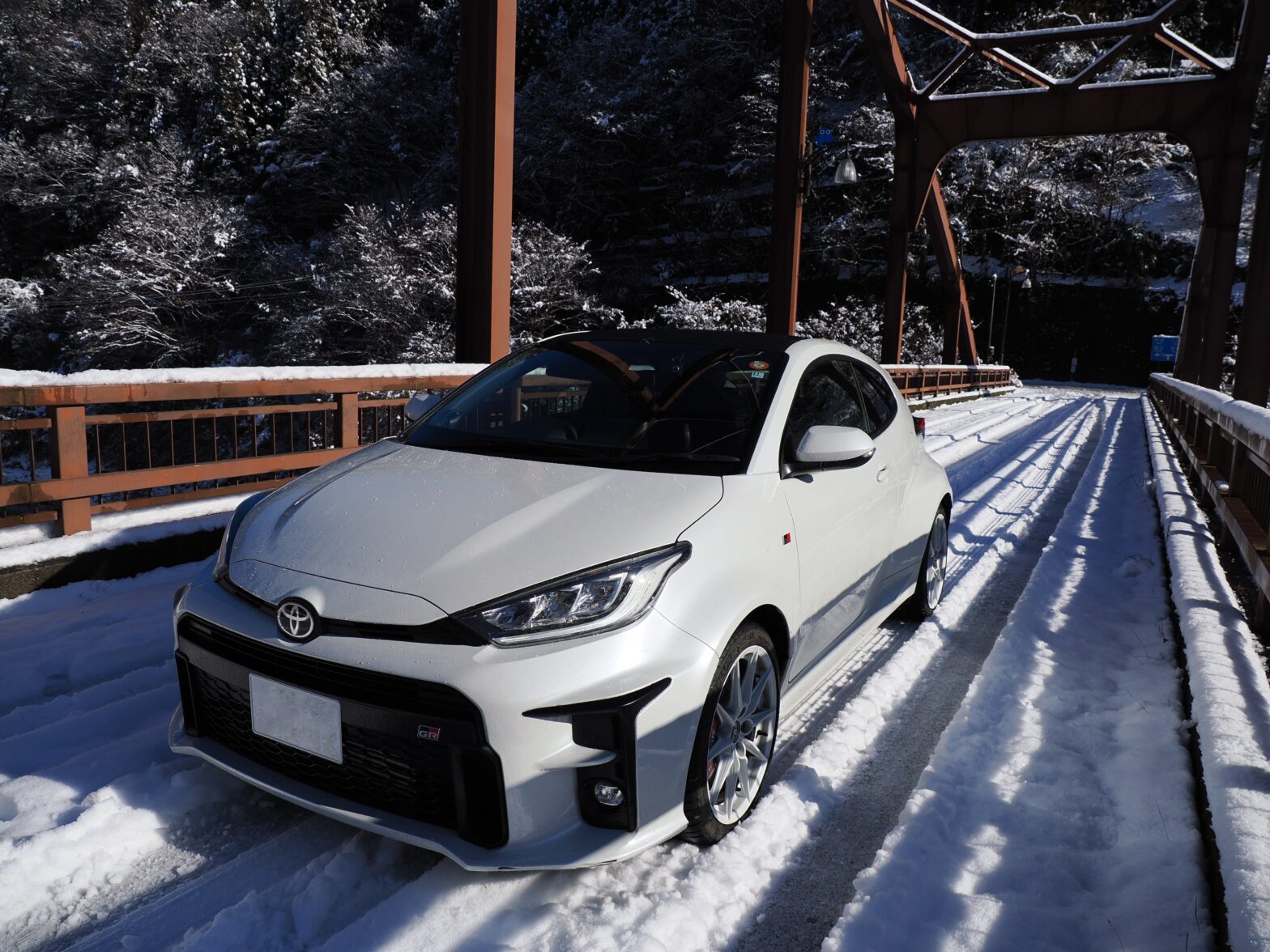 A GR Yaris parked on a road surface with snow ruts from accumulated snow.