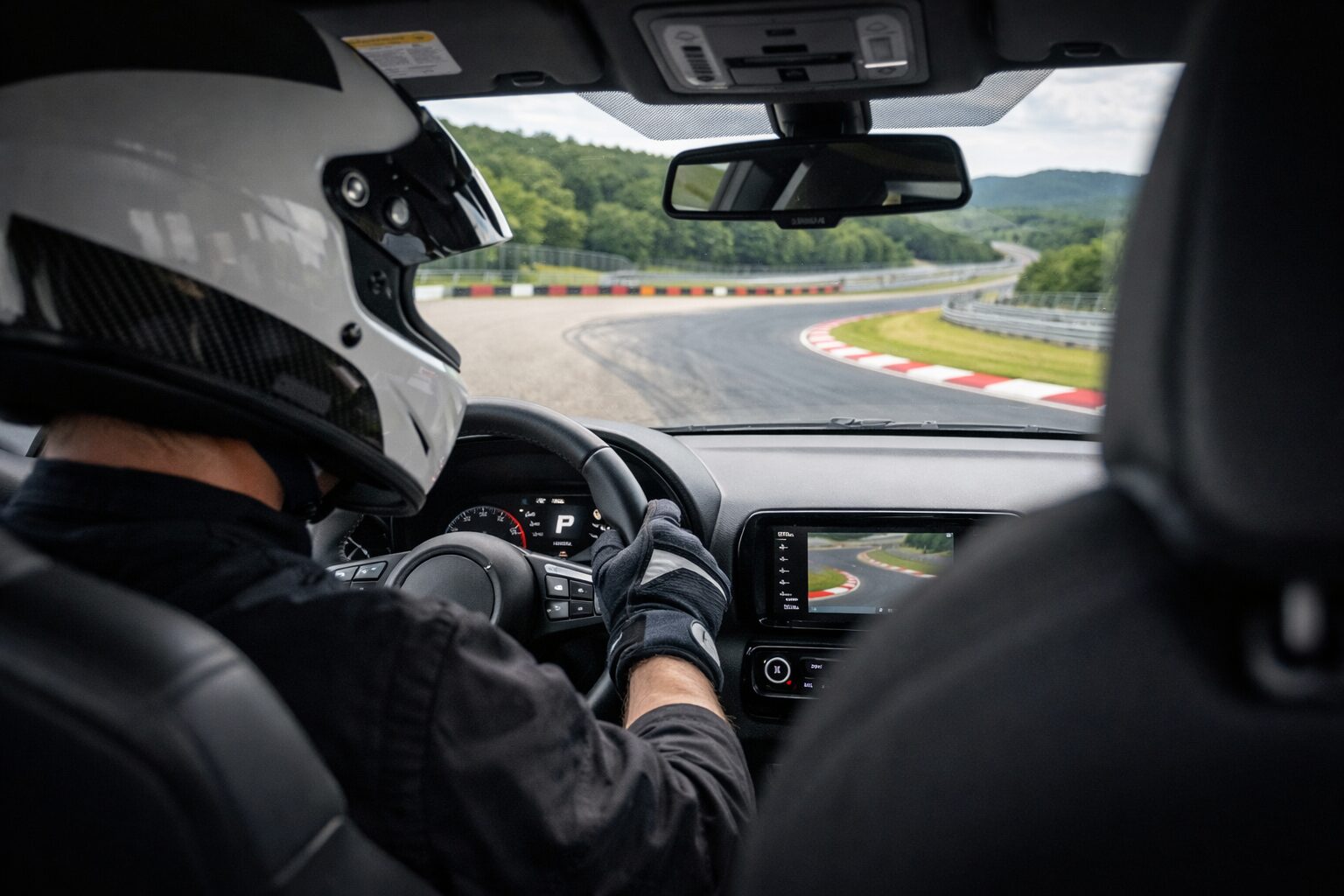 サーキットでプロレーサーのインストラクターが運転するGRヤリスの助手席から見た車内と左コーナーの走行風景